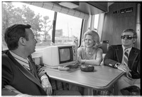 Carrie Nye sits at table of RV with two men