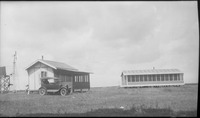 A car parked in front of a house and windmill