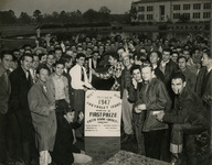 Crowd gathering around a poster promoting the prize for the "Fiesta Beard Contest"