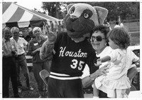 Cougar Mascot standing with a woman holding a small child