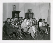 Several members of a band playing trombones, saxophones, and a flute