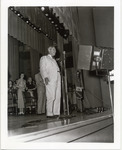 Hugh Roy Cullen standing at a microphone on a stage