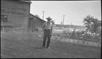 Man wearing a hat poses in front a house