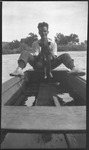 Man sitting in canoe, holding a pig