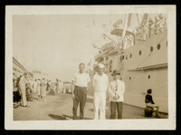 USS Houston (CA-30) docked with crew member and civilians standing on dock at port side of ship