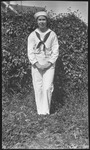 Woman in sailor's uniform in front of a hedge
