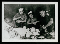 Harold McManus, Harry Stone, and unknown Australian squatting by corpse of Colonel Suga