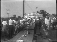 Crowd of people stand around benches 