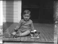Young boy sitting on a wooden deck