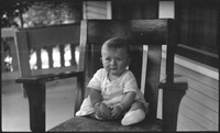 Baby sitting on front porch chair