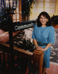 Portrait of Community host, Betti Maldonado, in front of Community sign