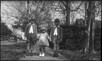 Two boys and a girl standing on a sidewalk