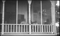 Three men sitting in rocking chairs on porch