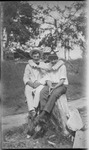 Three young men sitting on a tree stump