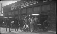 Group of people pose in front cars