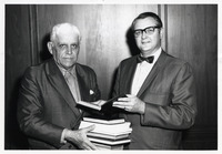 Edward G. Holley standing with a man holding books