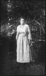 Woman in a dress standing amidst foliage