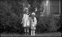 Two children posing in front of bush