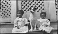 Two children sitting with dog on porch