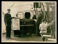 Capt. Guy Baker (right), with scroll from Cruiser Houston Committee and Christmas piano