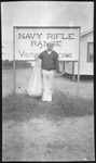 Sailor in front of a Navy rifle range sign