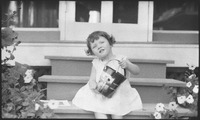 Girl sitting on porch steps holding pail