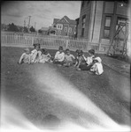 Several children sitting with a dog in a yard