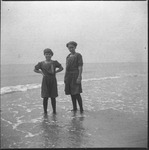 Two people with body of water standing on shoreline