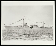USS Houston (CA-30) anchored at sea with flags flying and American flag prominent on stern