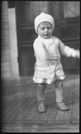 Toddler standing on porch wearing a hat