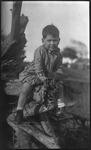 Boy sitting on fallen tree