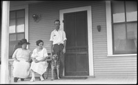 Two women and a man sitting on the front porch of a house