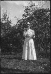 Woman in a white dress in front of foliage
