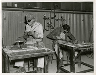 Two men welding at work tables